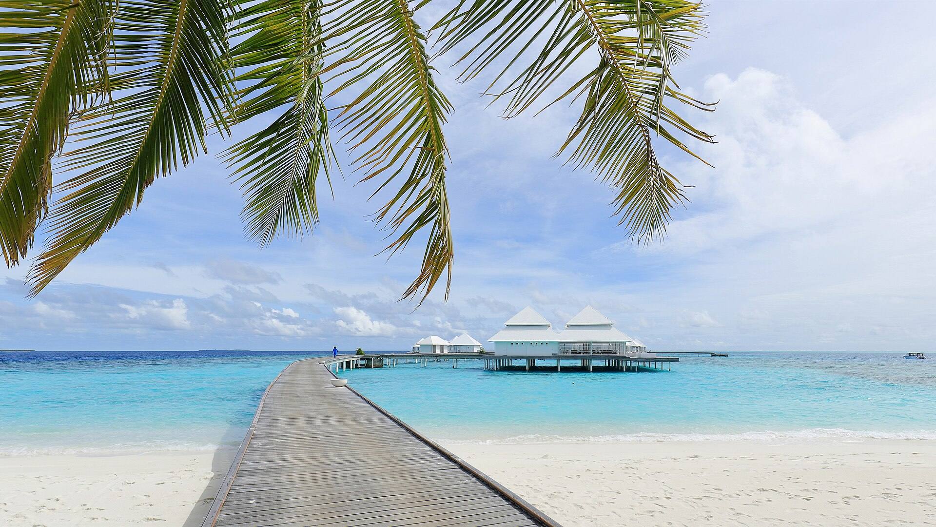 A jetty over clear water leading to water villas in the Maldives
